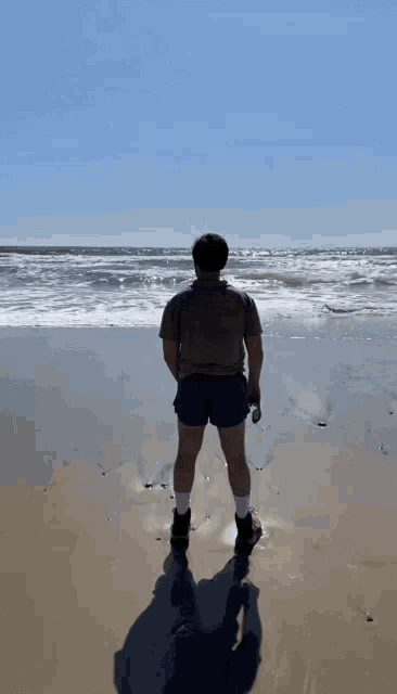 a man standing on a beach looking at the waves