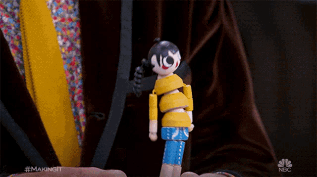 a close up of a person holding a toy with a nbc logo in the background