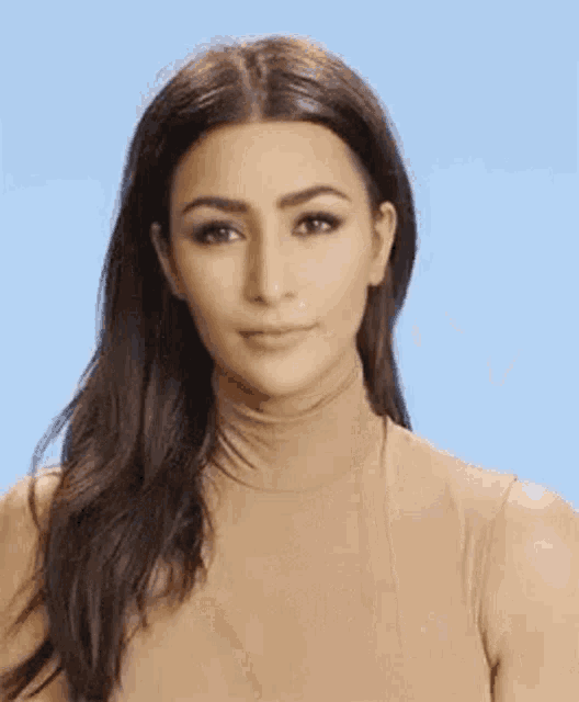 a close up of a woman wearing a tan turtleneck and making a funny face .