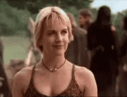 a woman in a tank top and choker is smiling in front of a crowd .