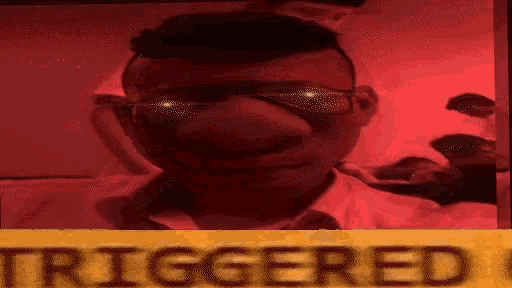 a man wearing sunglasses is behind a yellow sign that says triggered .