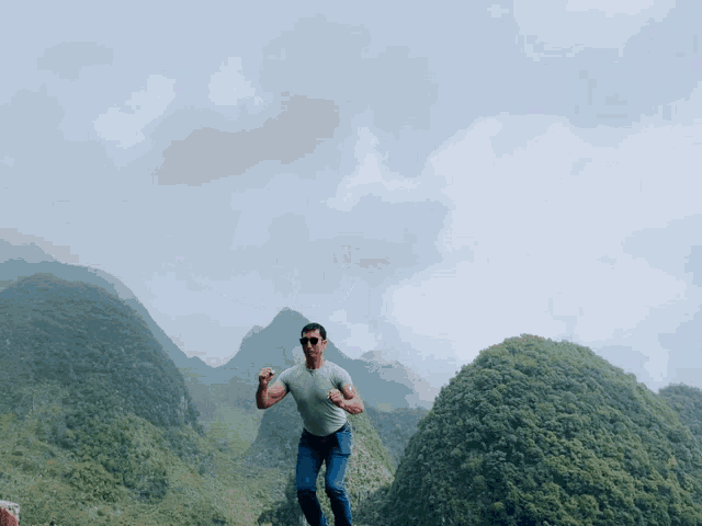 a man standing on top of a mountain with a cloudy sky behind him