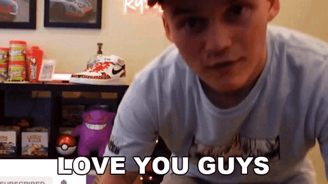 a man says " love you guys " in front of a shelf