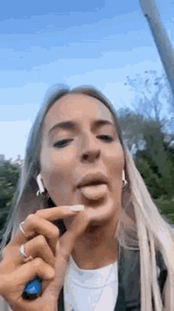 a woman is sticking her tongue out while wearing ear buds and a ring .