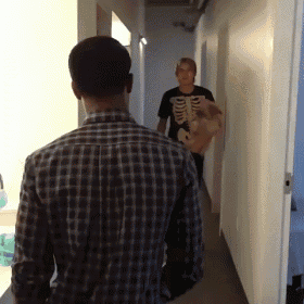 a man in a skeleton shirt is walking down a hallway