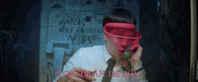 a man wearing a red visor is talking on a phone with the words " я оксан ты лох " on the bottom