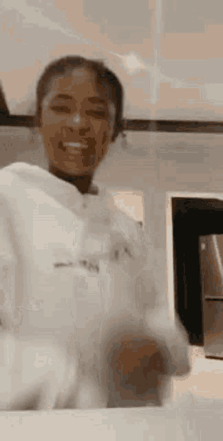 a woman in a white hoodie is standing in a kitchen .