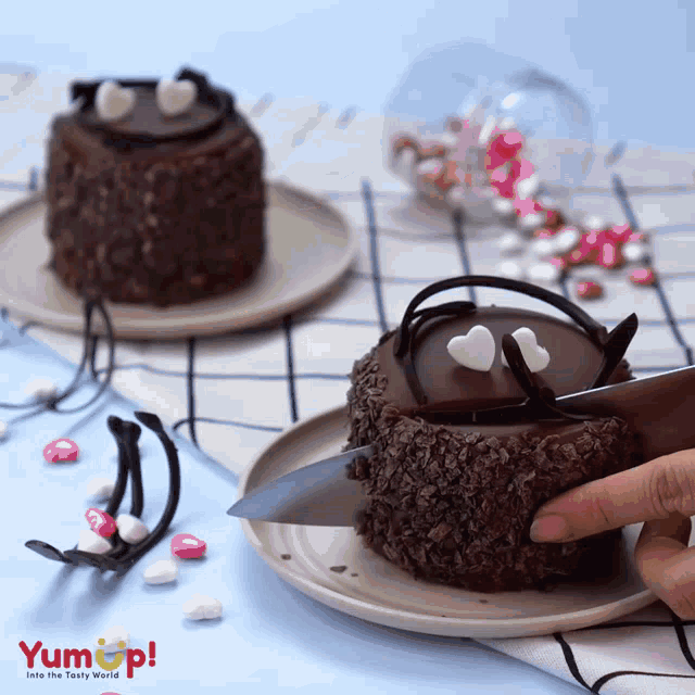 a person is cutting a chocolate cake on a plate that says yum up on it