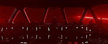 darth vader is sitting in the cockpit of a star wars ship looking out of the window .