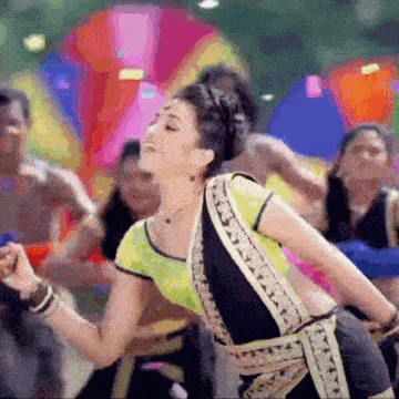 a woman in a green and black top is dancing in front of a crowd