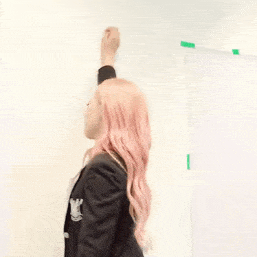 a woman with pink hair has her arm up in the air