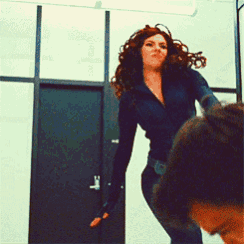 a woman in a black suit is kicking a man