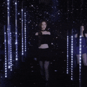 a woman wearing a black off the shoulder top is standing in front of a wall of lights .