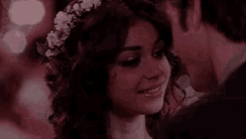 a man and a woman are kissing in a dark room . the woman is wearing a flower crown .