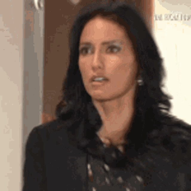 a woman with long dark hair is wearing a black jacket and a polka dot dress .