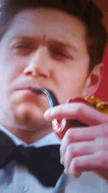 a man in a tuxedo is eating a sandwich with a fork in his mouth .