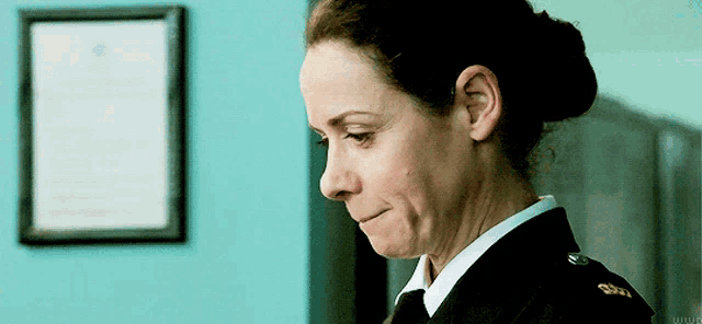 a woman in a military uniform is crying in front of a blue wall