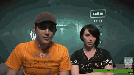 a man and a woman sit in front of a screen that says continue