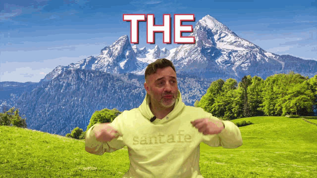 a man wearing a santafe sweatshirt is dancing in front of a mountain