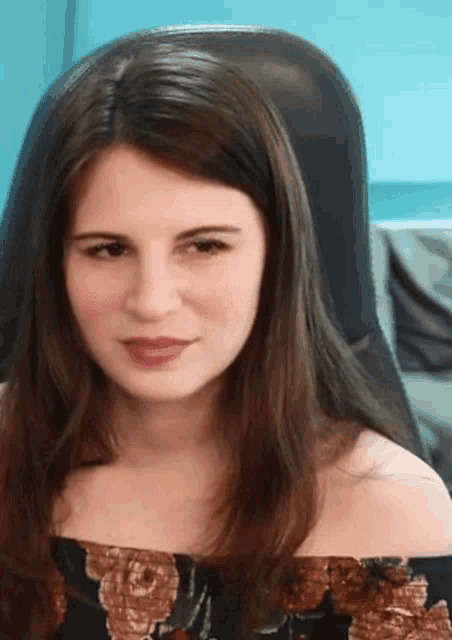 a woman sitting in a chair with a floral top on