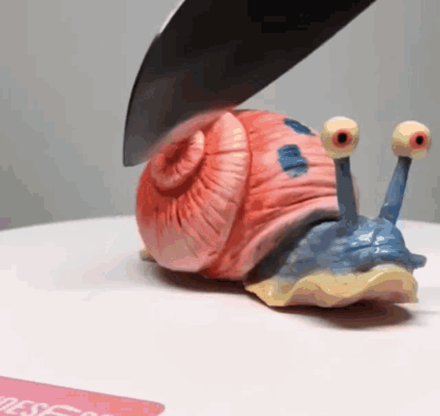 a spongebob snail is being sliced by a knife on a table