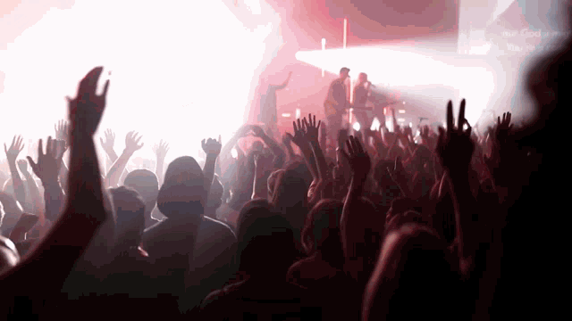 a crowd of people at a concert with their hands up
