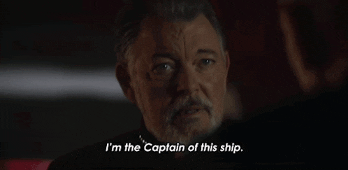 a man with a beard is talking to another man and says `` i 'm the captain of this ship . ''