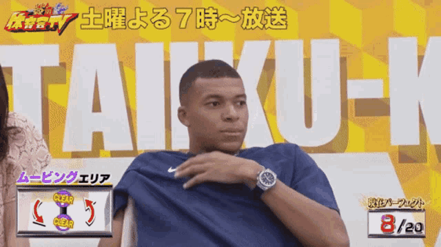 a man sitting in front of a sign that says taiku-k on it