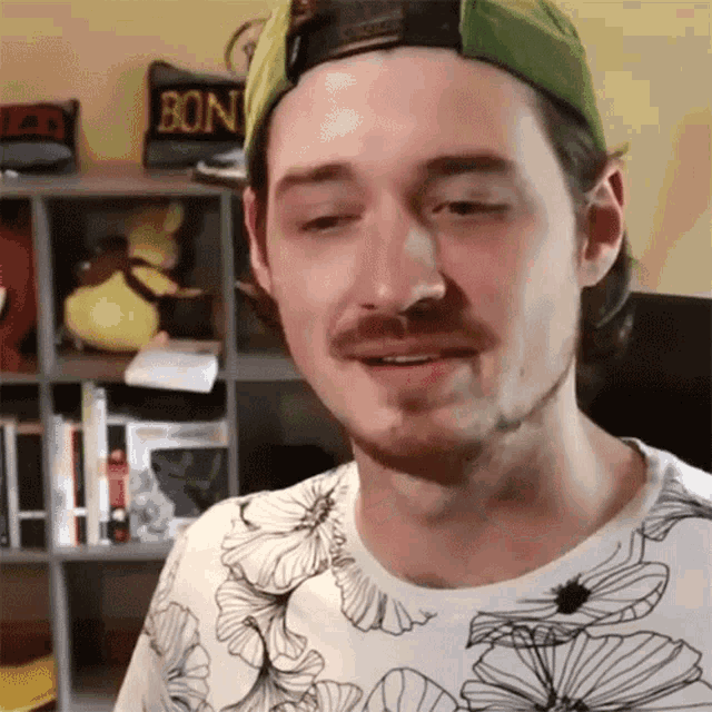 a man wearing a green hat and a floral shirt is smiling