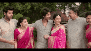 a group of people are posing for a picture and one of the women is wearing a pink saree