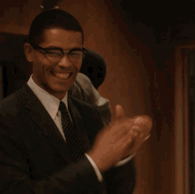 a man in a suit and tie is laughing with his mouth open