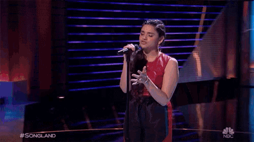 a woman singing into a microphone on a stage with the words songland on the bottom