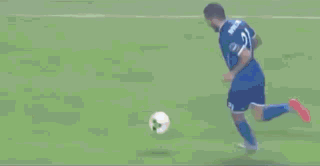 a man in a blue shirt is running on a soccer field .