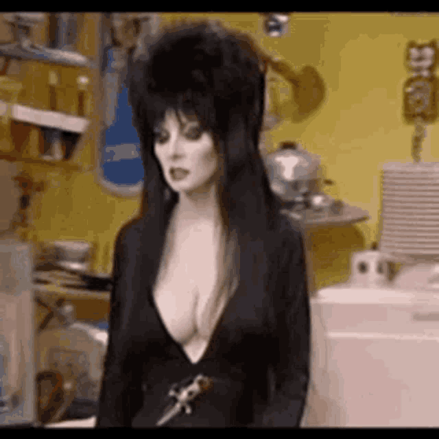 a woman in a very revealing black dress is standing in a kitchen .