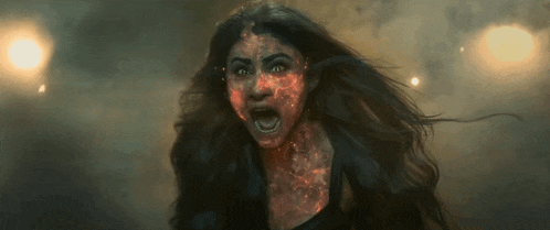 a woman with fire on her face is screaming in a dark room .