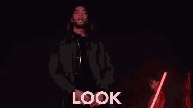 a man in a green jacket is giving a thumbs up and the word look is on the bottom