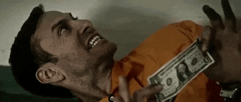 a man in a jail cell is holding a dollar bill in his hands .