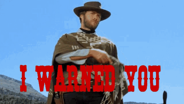 a man in a poncho stands in front of a sign that says " i warned you "