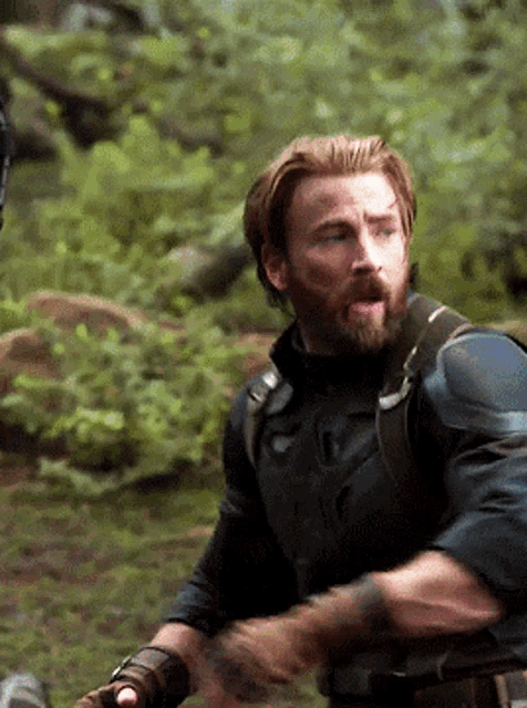 a man with a beard is standing in the woods with his tongue hanging out