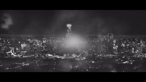 a black and white photo of a city at night with a tower in the distance