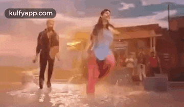 a man and a woman are dancing in a puddle of water in front of a building .