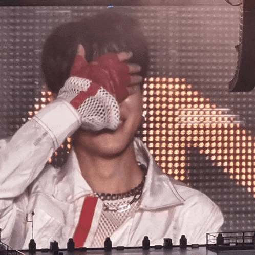 a person covering their face with their hand in front of a large screen