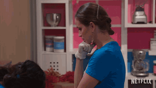 a woman in a blue shirt is talking on a phone with a netflix logo in the background