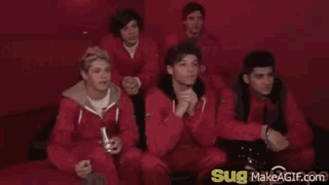 a group of men in red jumpsuits are sitting on a red couch .