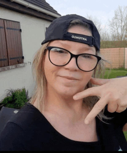 a woman wearing glasses and a black hat that says odi3tna on it