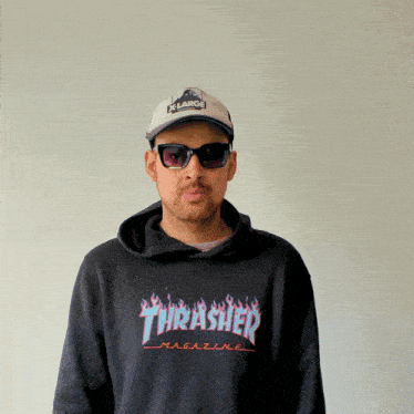 a man wearing sunglasses and a thrasher magazine sweatshirt