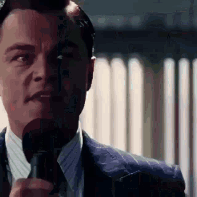 a man in a suit and tie holds a microphone