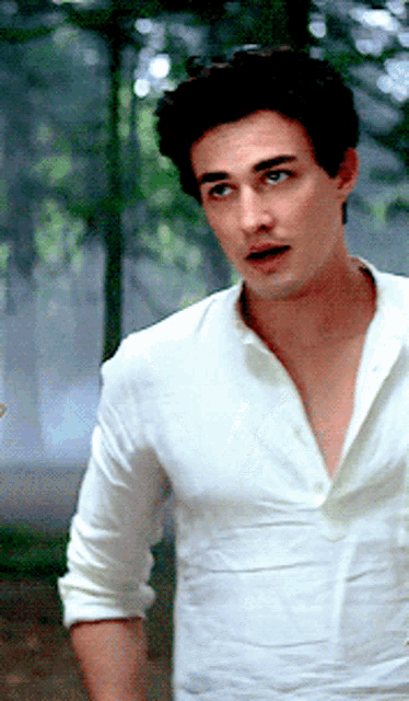 a man wearing a white shirt is standing in the woods