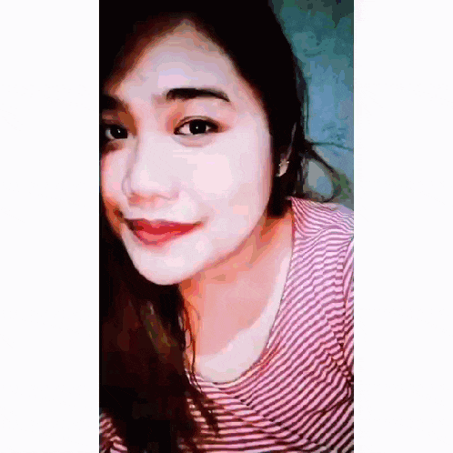 a close up of a woman 's face wearing a striped shirt and earrings .