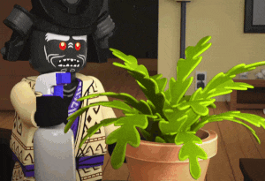 a lego figure is spraying a potted plant with a spray bottle